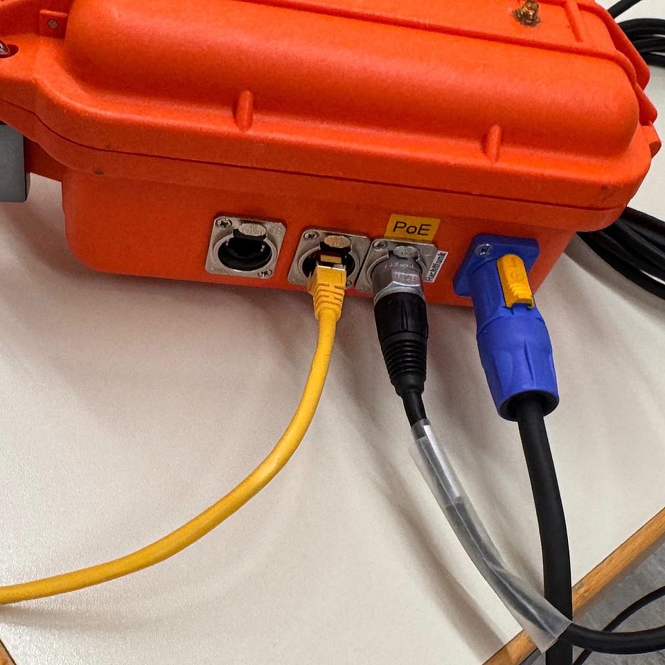 Das Foto zeigt einen orangefarbigen Verteilerkasten, an dem drei Kabel eingesteckt sind.